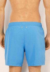 Pantaloni scurți de înot albaștri, cu un tiv elastic, detalii cu gromete la spate și un material neted, ușor.