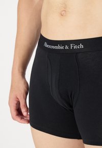 Sorte bomulds boxershorts med en tætsiddende pasform, udstyret med en elastisk talje med teksten "Abercrombie & Fitch" i hvid skrift.