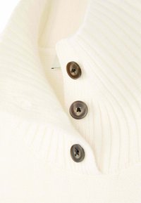 Weißer gestrickter Sweaterkragen mit drei braunen Knöpfen und geripptem Muster. Nahaufnahme, die die Knopfdetails und das Stoffmuster zeigt.