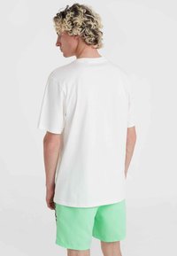 Camiseta blanca de algodón con mangas cortas, con un ajuste relajado. Combinada con pantalones cortos verde menta, que muestran una textura suave y un diseño simple.