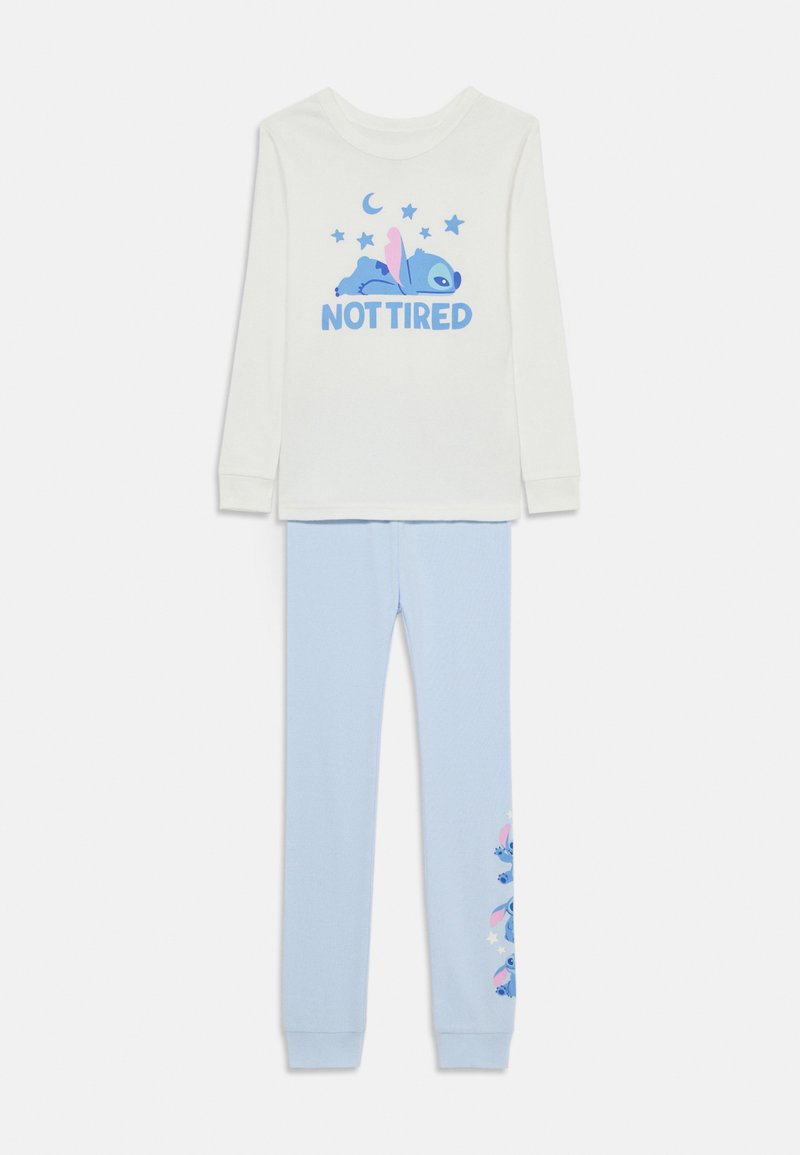 Hvid langærmet top med blå tekst og grafik "NOT TIRED". Lyseblå pyjamasbukser med tekstureret finish og mønster af tegneseriefigurer.