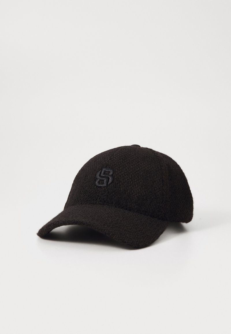 Casquette de baseball en tissu noir texturé avec visière incurvée et lettre S brodée à l'avant, présentée sur fond blanc uni.