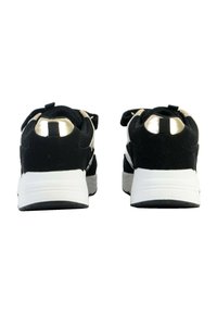 Scarpe sportive nere con una tomaia strutturata, dettagli metallici dorati sul tallone e una suola intermedia bianca. Presentano un collare imbottito e una fascia.