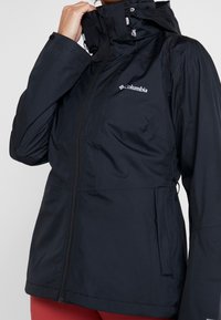 Zwarte waterdichte jas met een ritssluiting aan de voorkant, verstelbare capuchon en zakken. Kenmerkt zich door het Columbia-logo op de borst. Glad, duurzaam stof.