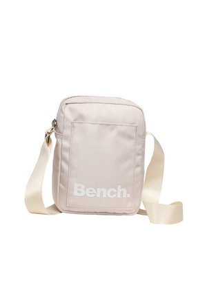 Petit sac bandoulière beige avec poche avant, sangle blanche réglable et logo "Bench." blanc sur la poche avant.