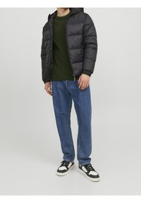 Sort dunjakke med hætte, grøn strikket sweater under, blå jeans med lige ben og sorte sneakers med hvide detaljer.