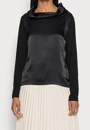 Sort langærmet bluse med satin cowl-neck design. Materialet står i kontrast til en plisseret, lyse farvet nederdel. Glat tekstur.