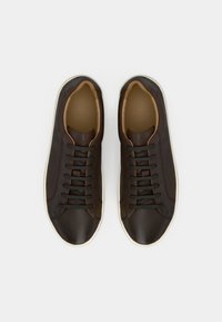 Bruna sneakers i läder med rundad tå, snörningsdesign, beige detaljer och krämfärgade sulor. Slät textur med sydda detaljer.