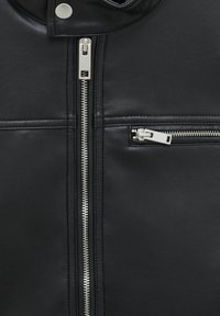 Veste en cuir noir avec fermeture éclair centrale, poche zippée sur le côté et texture lisse avec des détails de couture visibles.