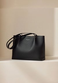 Schwarze Leder-Umhängetasche mit strukturierter Oberfläche, dünne Schulterriemen und einem minimalistischen Design. Elegant und schlicht.