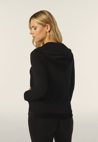 Felpa nera con una texture morbida, dotata di cappuccio e orlo a coste. Design semplice con maniche lunghe e vestibilità comoda.