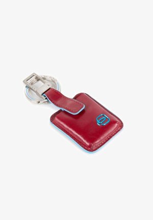 Porte-clés en cuir rouge avec des accents bleus, featuring a silver metal keyring et un design de pochette rectangulaire pour un rangement sécurisé.
