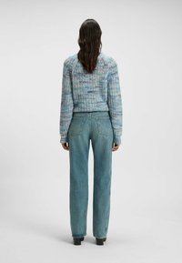 Ljusblå tröja med strukturerad stickad mönster, kombinerad med hög midja, avslappnade ljusblå jeans. Båda har en avslappnad design.