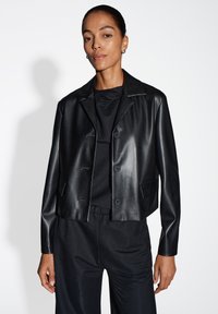 Zwarte cropped leren jas met een klassieke kraag, drie knopen en twee voorzakken, gecombineerd met een bijpassend zwart topje en broek.