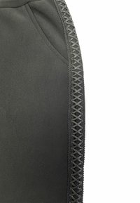 Black garment with a smooth texture and a decorative woven pattern along the side, featuring a pocket on the left.