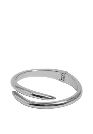 Pulsera brazalete de metal con tono plateado, diseño liso y curvado, con un cierre de bisagra discreto para abrir y cerrar.