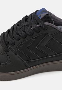 Czarne sneakersy z cholewką ze skóry, z fakturowanymi akcentami, kontrastującą szarym podeszwą oraz niebieskim detalem na języku, z tradycyjnym sznurowaniem.