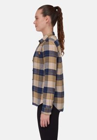 Camicia a quadri nei toni blu, giallo e grigio; chiusura con bottoni davanti, colletto e maniche lunghe; parte posteriore leggermente più lunga; il tessuto appare morbido.