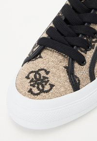 Béžové tkané tenisky s černými vzorovanými akcenty, černými tkaničkami a bílou gumovou podrážkou; mají strukturovaný textilní svršek.