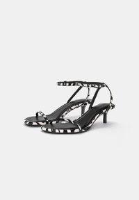 Sandales à talons à imprimé zèbre noir et blanc avec de fines lanières, bout ouvert et petit talon aiguille, dotées d'une doublure intérieure noire lisse.