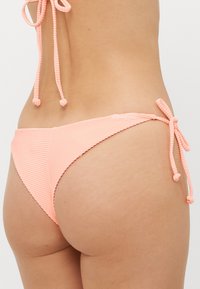 Rosa randig bikiniunderdel med låg midja, med sidoband. Tyget är slätt med en lätt lyster och mjuk textur.