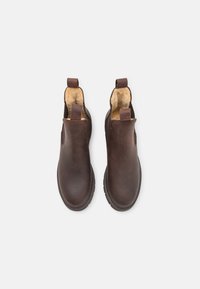 Botas de cuero marrón hasta el tobillo con forro de pelo, paneles laterales elásticos y tiradores en la parte posterior; punta redonda y suela texturizada.