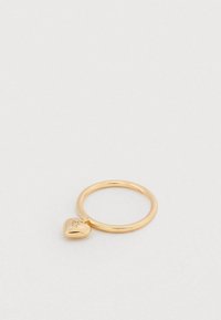 Kuldne sõrmus väikese südamekujuga ripatsiga, millele on graveeritud initsiaalid ja mis sisaldab väikest kivikest, valgel pinnal.