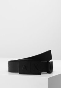 Sort bælte lavet af tekstureret syntetisk materiale, med en rektangulær spænde og hævet "AX"-logo. Enkel og moderne design.