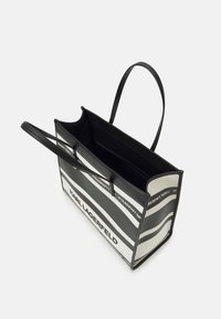 Sac fourre-tout noir et blanc de forme rectangulaire, présentant des rayures horizontales et le texte "KARL LAGERFELD." Conception à ouverture supérieure, matériau en tissu.