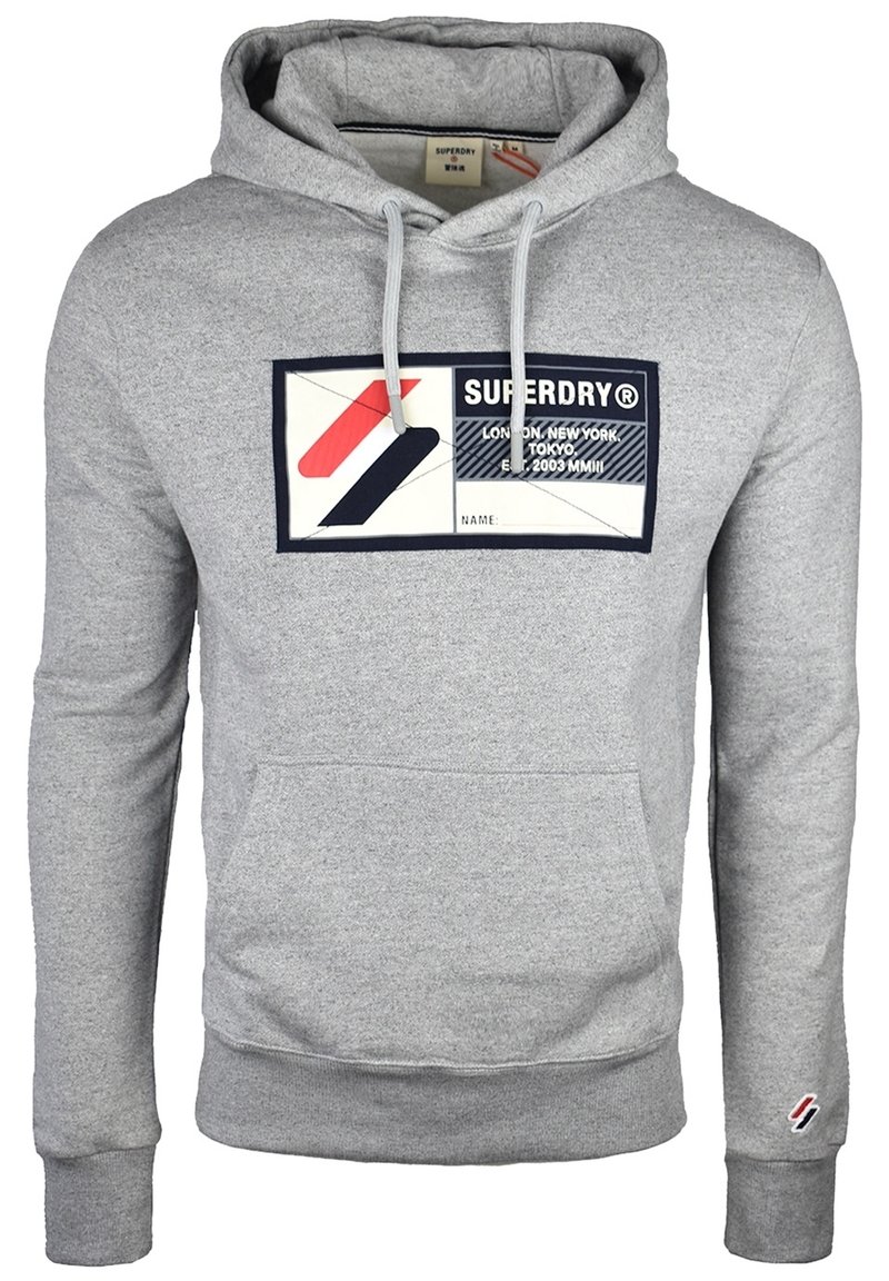 Sudadera con capucha gris hecha de una mezcla de algodón, que presenta un bolsillo tipo canguro en la parte delantera y un parche gráfico con logotipo en rojo, negro y blanco.