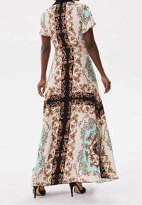 Robe maxi en tissu léger avec un motif paisley en beige, teal et marron, dotée de manches courtes et d'une silhouette fluide.