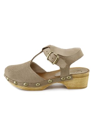 Sandalia estilo zueco de ante beige con tira en T, hebilla dorada, tachuelas decorativas de latón y tacón bajo de bloque de madera.