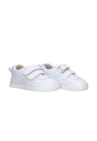 Un par de zapatos blancos para niño pequeño con doble strap de Velcro y forro interior beige, suela de goma ligera para un fácil uso.
