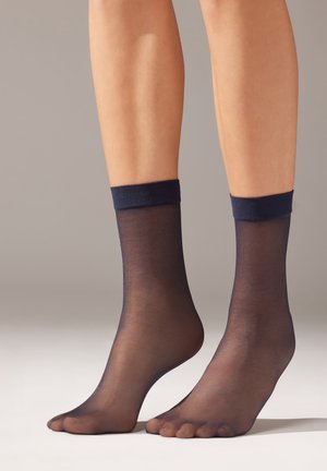 Genomskinliga navy ankelsockor med en mjuk, texturerad kant. Materialet är lätt och något genomskinligt, vilket avslöjar huden under.