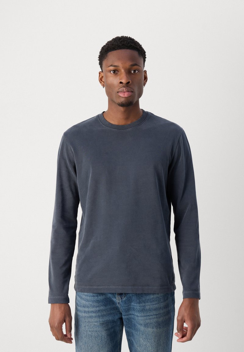 Langärmliges, Rundhalshemd in dunkelgrau, aus weichem Baumwollstoff. Bietet eine lässige Passform und dezente Nähte entlang des Ausschnitts und Saums.