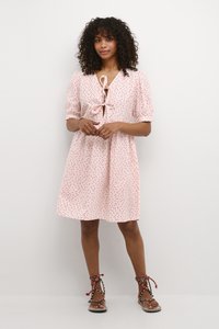 Rosa Kleid mit kurzen Puffärmeln, taillierter Taille und Bindedetail am Ausschnitt. Hat rote Punkte und besteht aus leichtem Stoff.