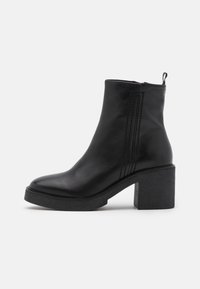 Black leather ankle boots featuring a chunky heel, rounded toe, and side stitching details, with a textured black platform sole.