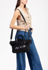 Borsa intrecciata nera con parte superiore frangiata, dettagli in pelle e "Playa del Mar" ricamato in bianco. Caratterizzata da manici doppi e una tracolla.