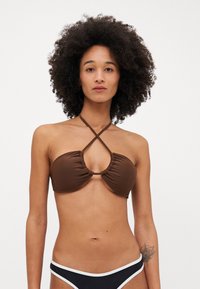 Hnědé bikinové top s nařaseným designem a předním výřezem, se zkříženými ramínky. Černé dno s bílým lemem. Hladká textilie.
