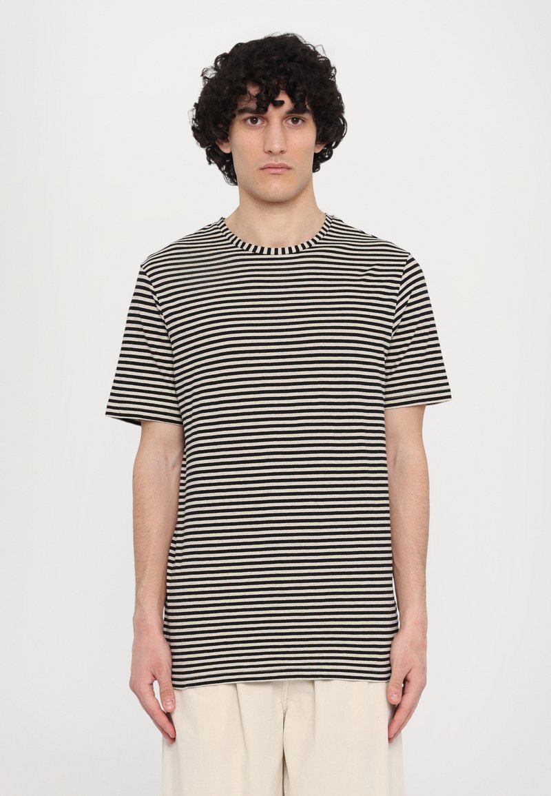 Tricou cu dungi, având dungi orizontale negre și bej, mâneci scurte, guler rotund și o croială lejeră. Material din bumbac cu o textură moale.
