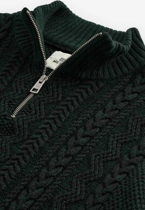 Tmavo zelený pletený pulóver s vysokým golierom a strieborným zipsom. Obsahuje štruktúrovaný, zigzagový vzor a rebrované akcenty na výstrihu.
