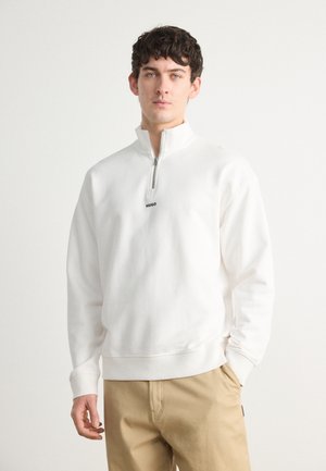 Vit zip-neck sweatshirt med subtil elastisk nederkant och ärmslut, med en liten svart "HUGO"-logotyp på bröstet. Standard passform.