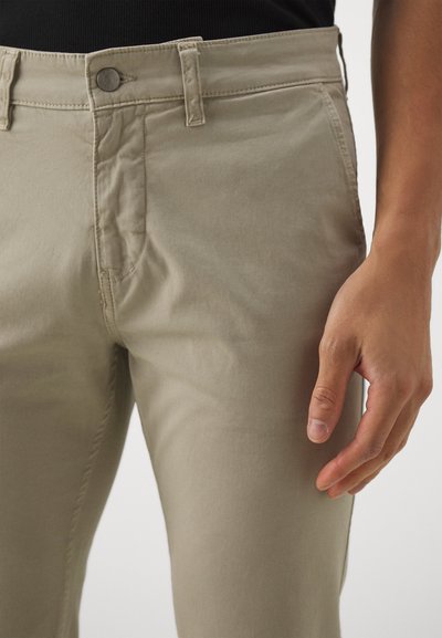 Beige chinos with a zipper fly, button closure, and a slim fit. Features front pockets and a smooth, cotton texture.