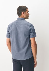 Chemise à manches courtes avec boutons en bleu marine à motif texturé. Tissu lisse, dotée d'un col et d'un ourlet droit.