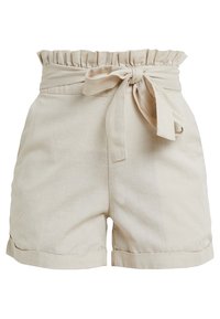 Beżowe lniane szorty z falbaną w pasie i przewiązaną kokardą, charakteryzujące się luźnym krojem i wywiniętymi nogawkami dla uporządkowanego wyglądu.