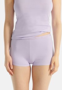 Woman wearing light purple tank top and matching fitted shorts, shown from shoulders to mid-thigh against white background.