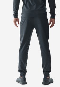 Pantalones deportivos grises con un corte ajustado, hechos de una tela suave y elástica. Los dobladillos ajustados y los bolsillos laterales mejoran la funcionalidad.