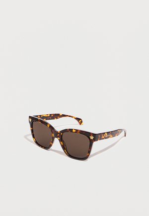 Gafas de sol rectangulares de carey con lentes oscuras y logos dorados de Medusa en las esquinas frontales y las patillas sobre un fondo blanco.