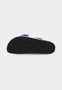 Μαύρη υφασμάτινη σόλα ενός ανοιχτού γαλάζιου σανδαλιού με δύο ρυθμιζόμενους ιμάντες, εμφανιζόμενο από κάτω με φόντο απλό λευκό.