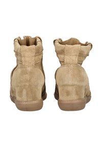 Botines de ante color canela con parte superior texturizada, punta redondeada y tacón bajo de goma. Presentan detalles de costura a lo largo de los laterales y la parte trasera.